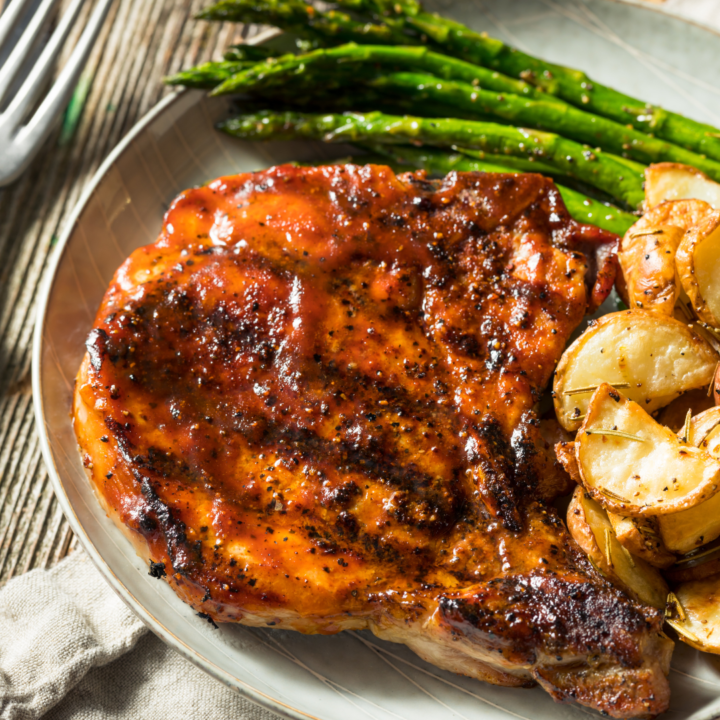 glazed pork chop with potatoes and asparagus.