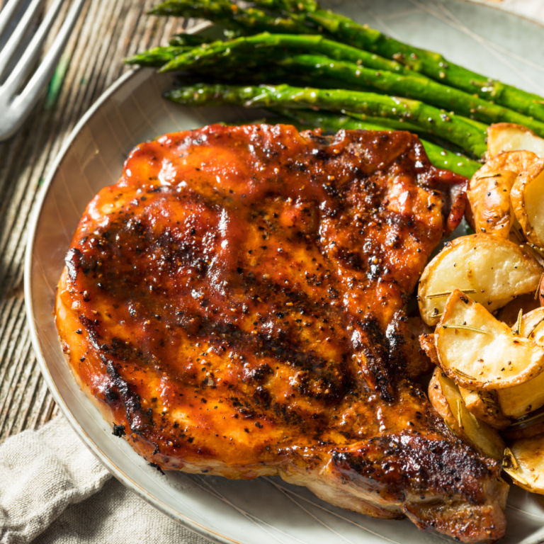 glazed pork chop with potatoes and asparagus.